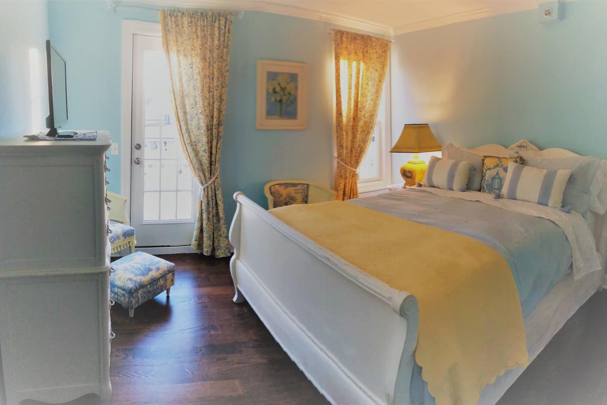 A bedroom with a bed, a chair, a dresser, and a lamp.