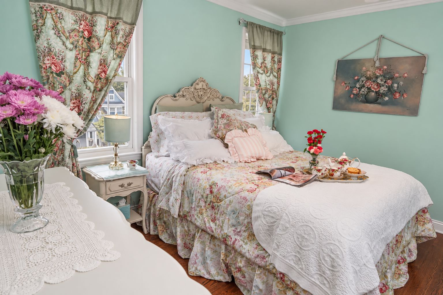 A bedroom with a floral bedspread, a bedside table with a lamp, and a window with curtains.