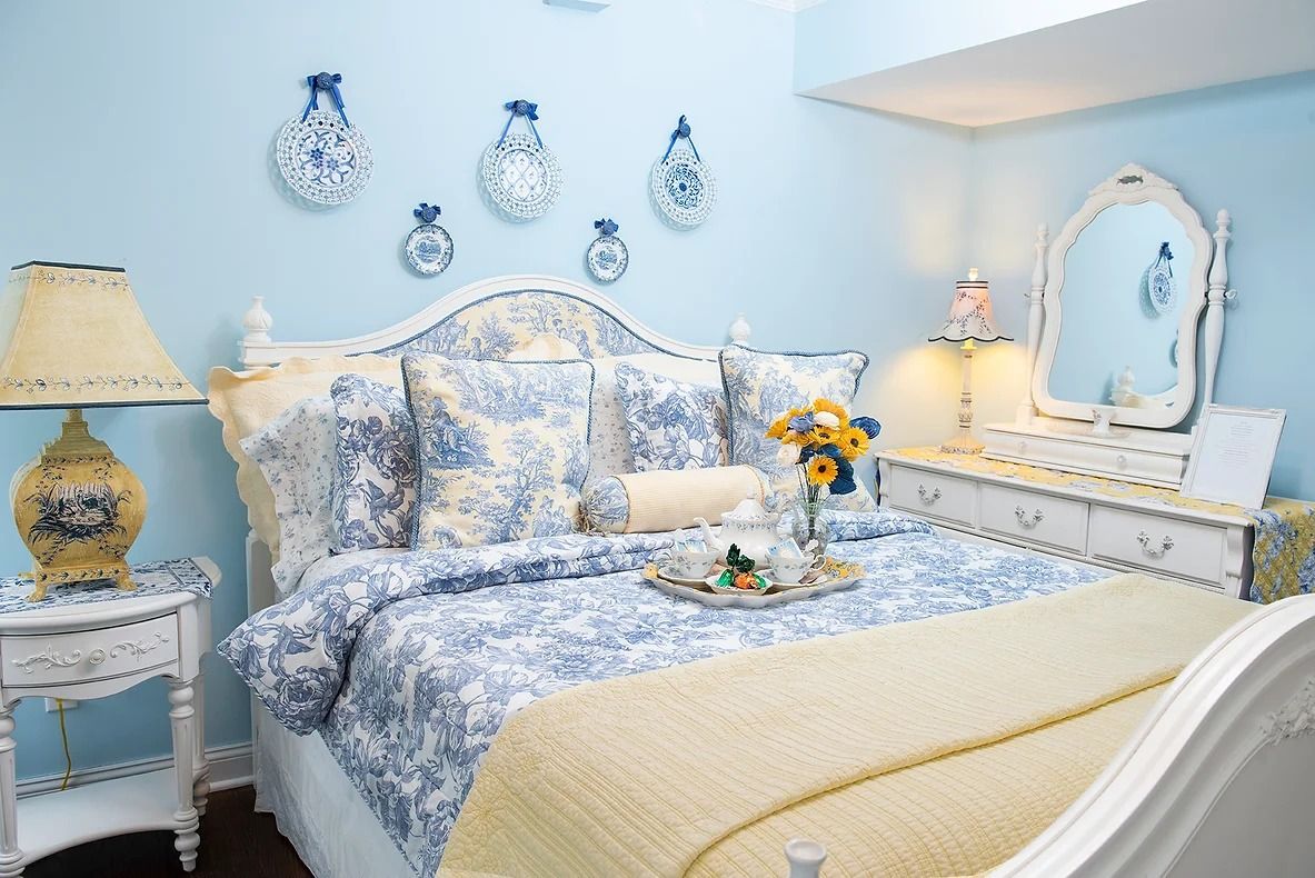 Ein Schlafzimmer mit Bett, Nachttischen, Kommode, Spiegel und Wanddekorationen.