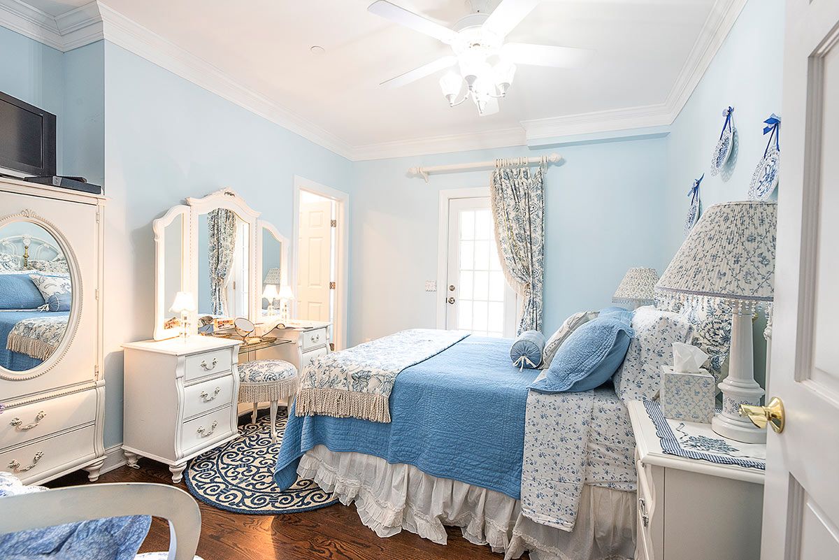 Quarto com cama, cômoda, penteadeira e ventilador de teto.