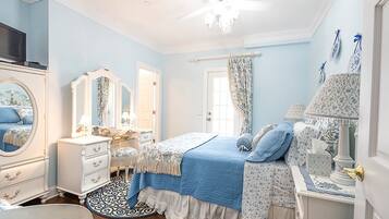 Quarto com cama, cômoda, penteadeira e ventilador de teto.