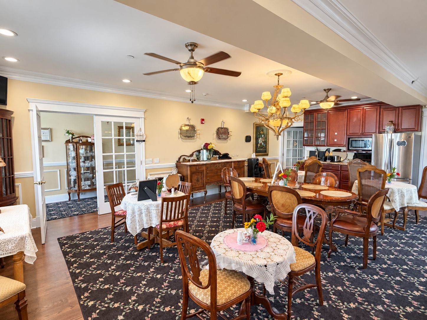 A spacious dining area with multiple tables and chairs, a ceiling fan, and a kitchen area with wooden cabinets and appliances.