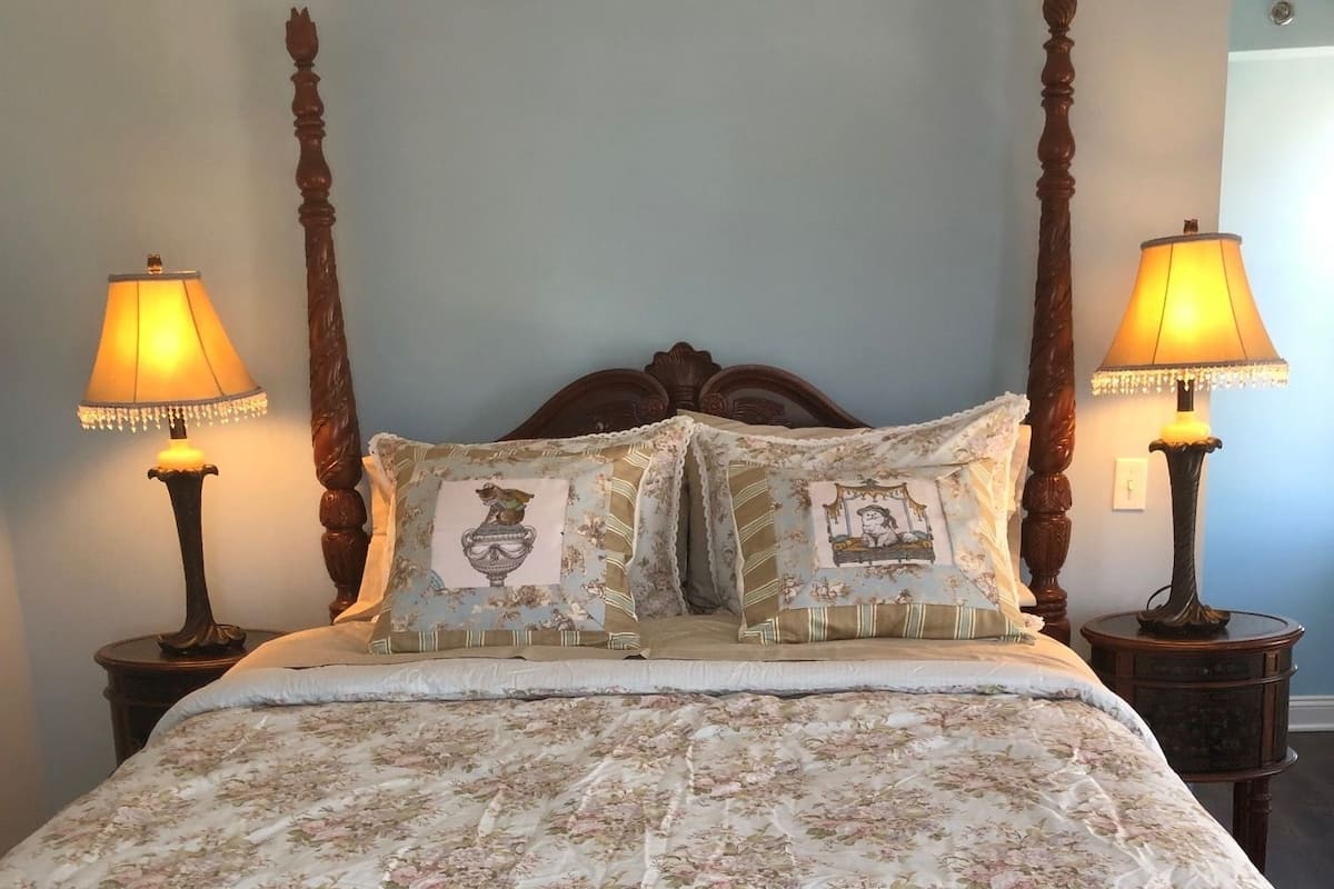 A bed with a floral bedspread, two nightstands with lamps, and a wooden headboard.