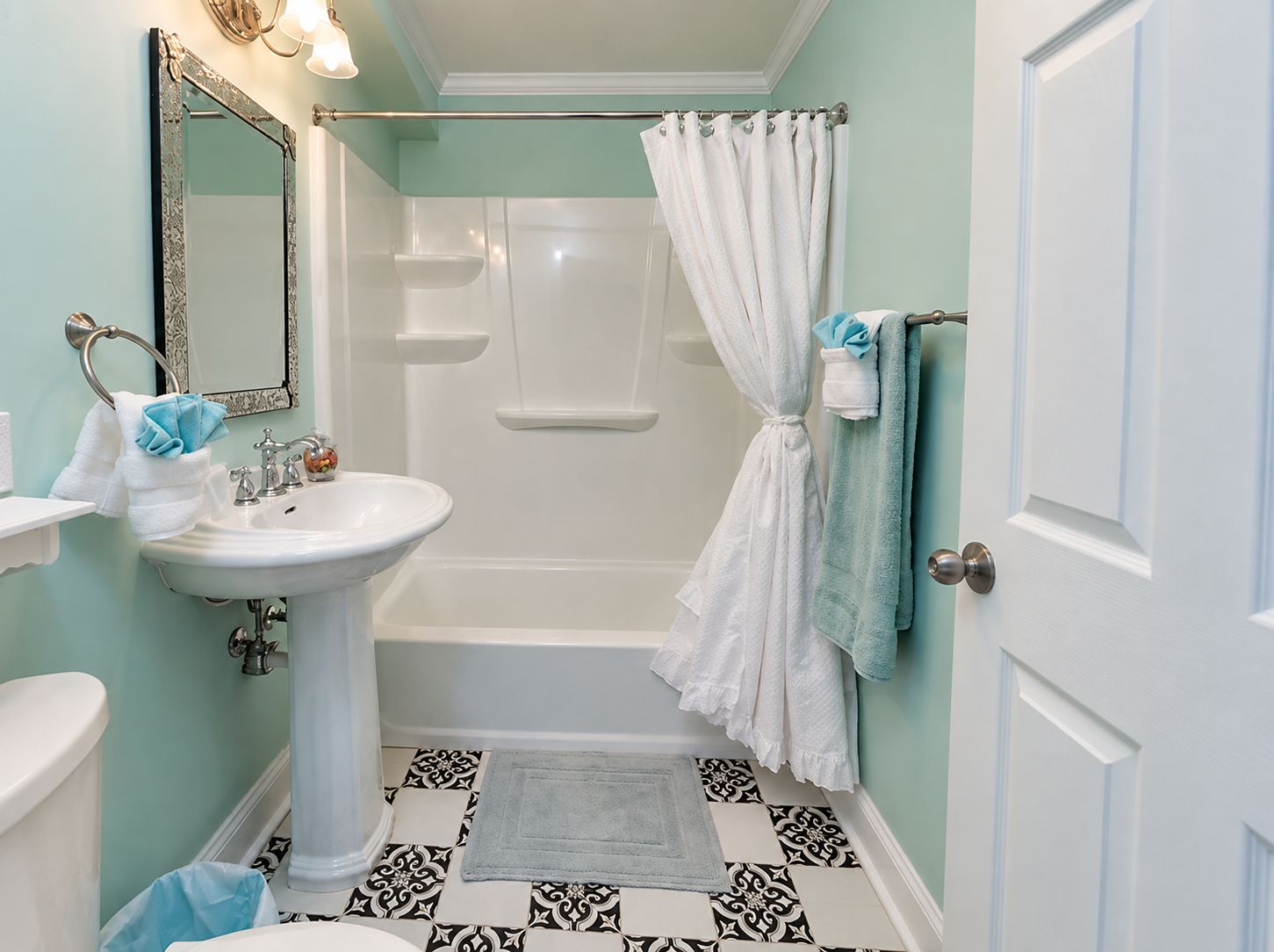 Une salle de bain avec un lavabo blanc, une baignoire et un rideau de douche.