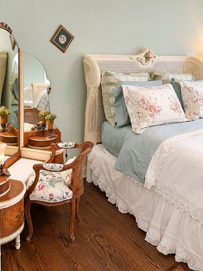 A bedroom with a bed, a chair, a dresser, a mirror, and a wall-mounted picture frame. - The Carriage House B&B (Ocean Grove)