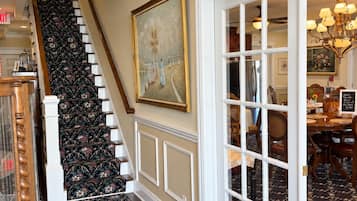 A staircase with a patterned carpet leading to a dining area with a chandelier.