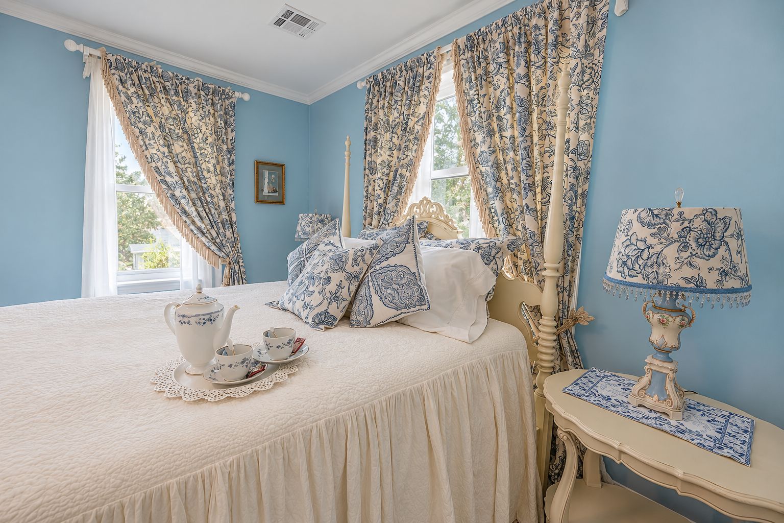A bedroom with a bed, a bedside table with a lamp, and curtains with a floral pattern.