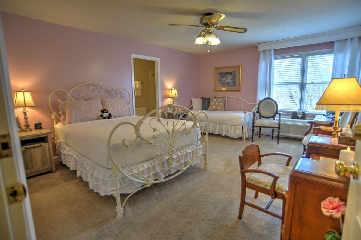 Une chambre à coucher avec un lit blanc à baldaquin, un ventilateur de plafond, un bureau avec une lampe et une chaise.