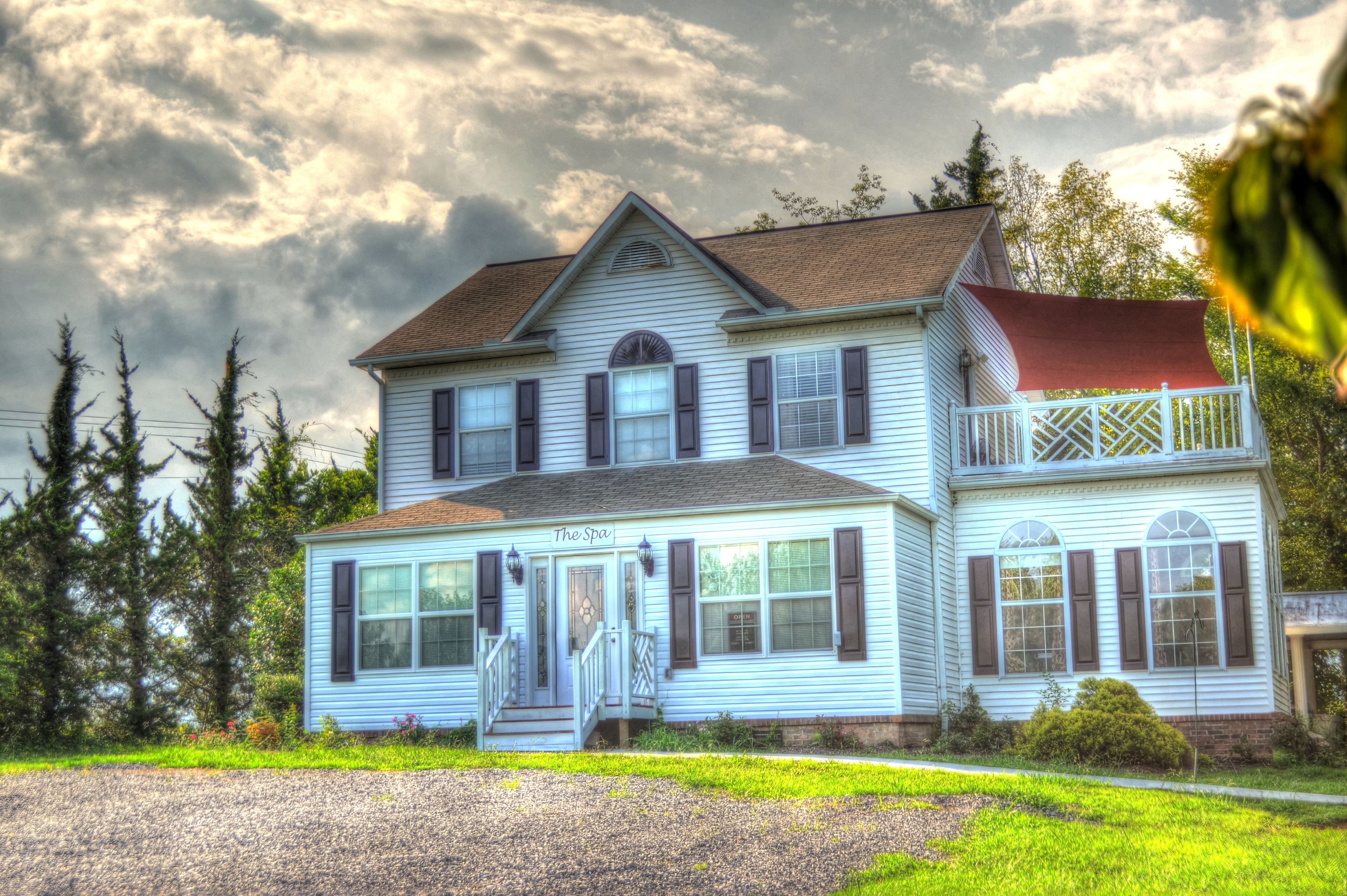 A two-story house with a porch, a red awning, and a sign that reads "The Spa."