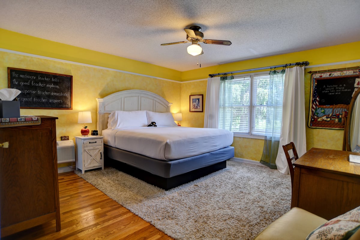 Une chambre à coucher comprenant un lit, des tables de chevet, une commode, un bureau et une chaise.