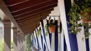 A covered outdoor seating area with rows of benches and hanging planters. - Casa Laguna Hotel & Spa (Laguna Beach)