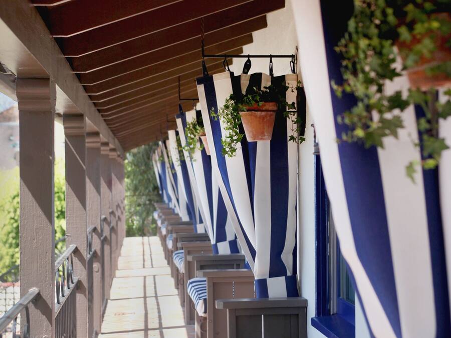 A covered outdoor seating area with rows of benches and hanging planters.