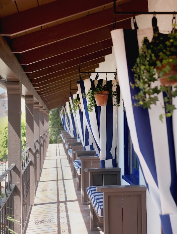 A covered outdoor seating area with rows of benches and hanging planters. - Casa Laguna Hotel & Spa (Laguna Beach)