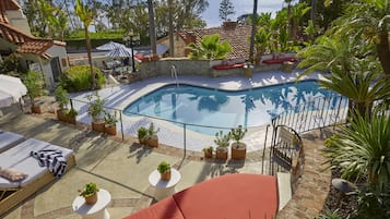 Ein Poolbereich mit Liegestühlen, einem kleinen Pool und Pflanzen in Töpfen.