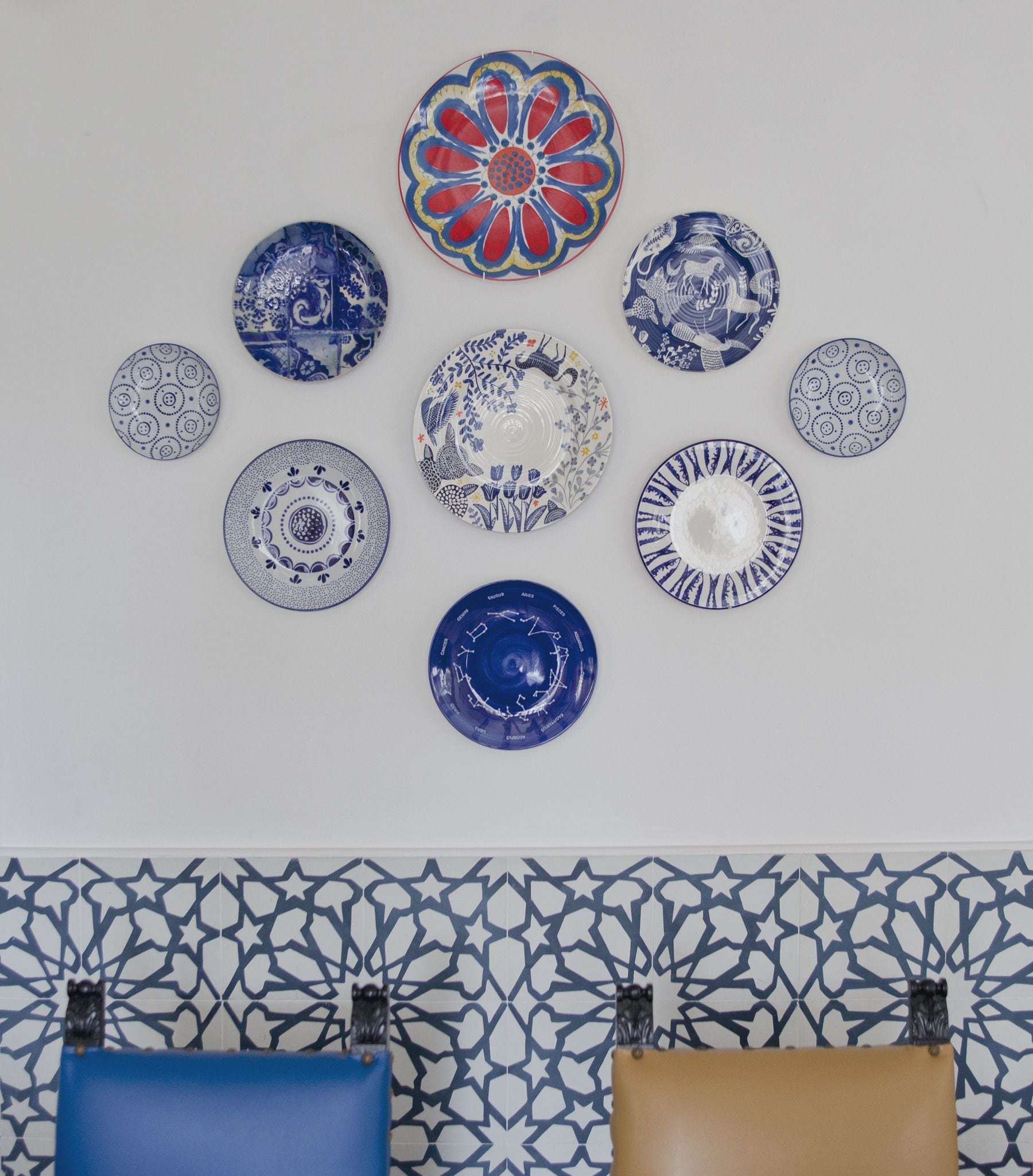 Een verzameling decoratieve borden, geplaatst op een muur met een betegelde achtergrond.