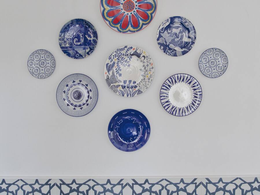 Een verzameling decoratieve borden, geplaatst op een muur met een betegelde achtergrond.