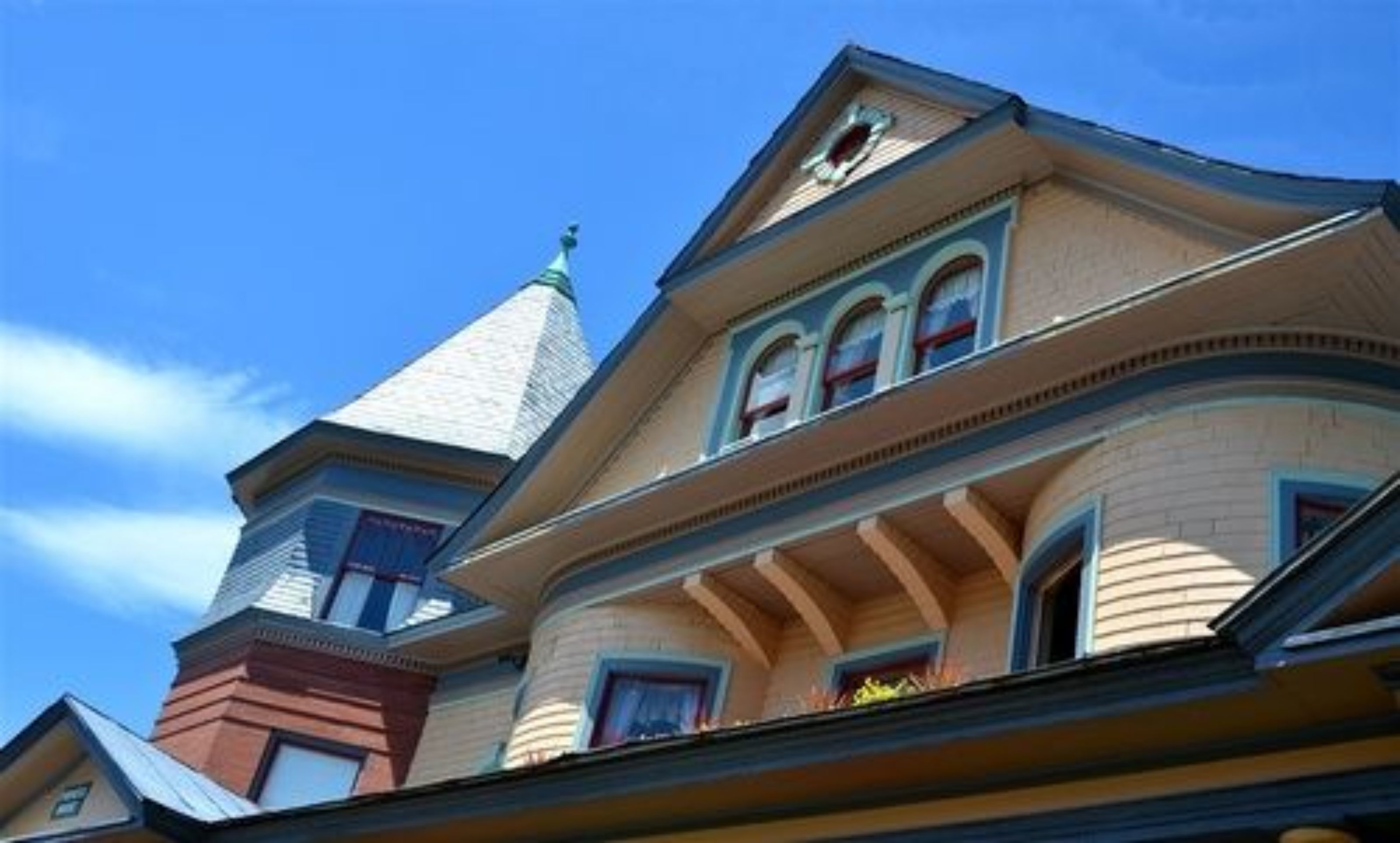 Un edificio de estilo victoriano con una torre destacada y ventanas de arco.