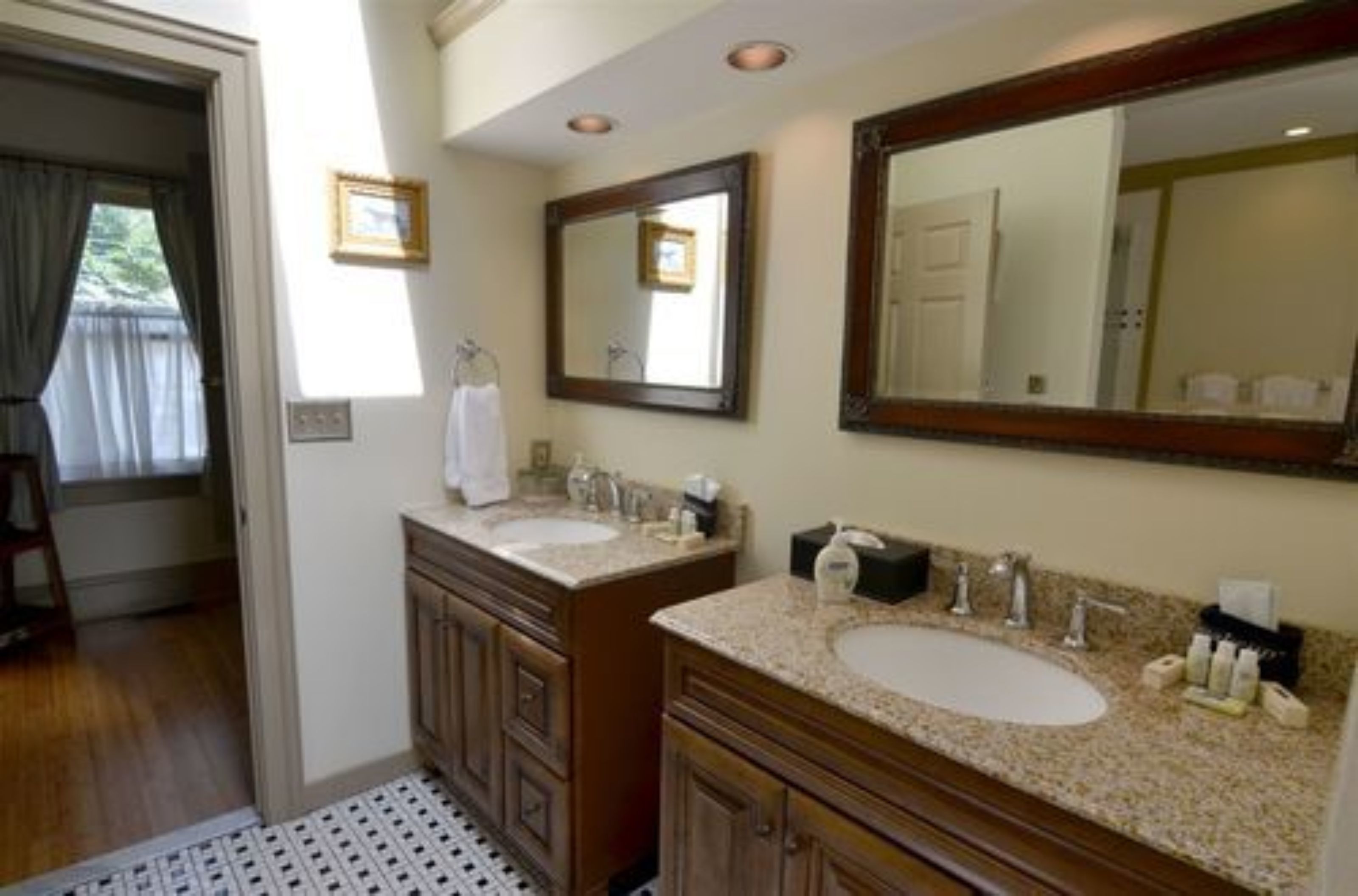 A bathroom with two sinks, a large mirror, and a wooden vanity.