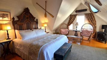 A cozy attic bedroom with a large bed, wooden headboard, and a rustic fireplace.
