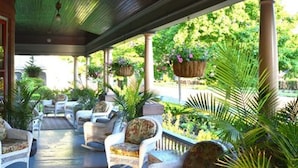 A covered outdoor seating area with wicker furniture and hanging planters.