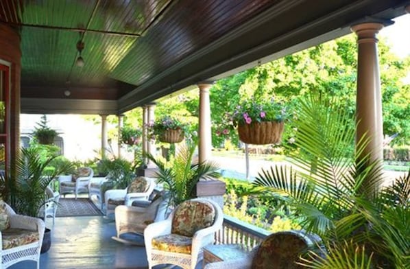 A covered outdoor seating area with wicker furniture and hanging planters.