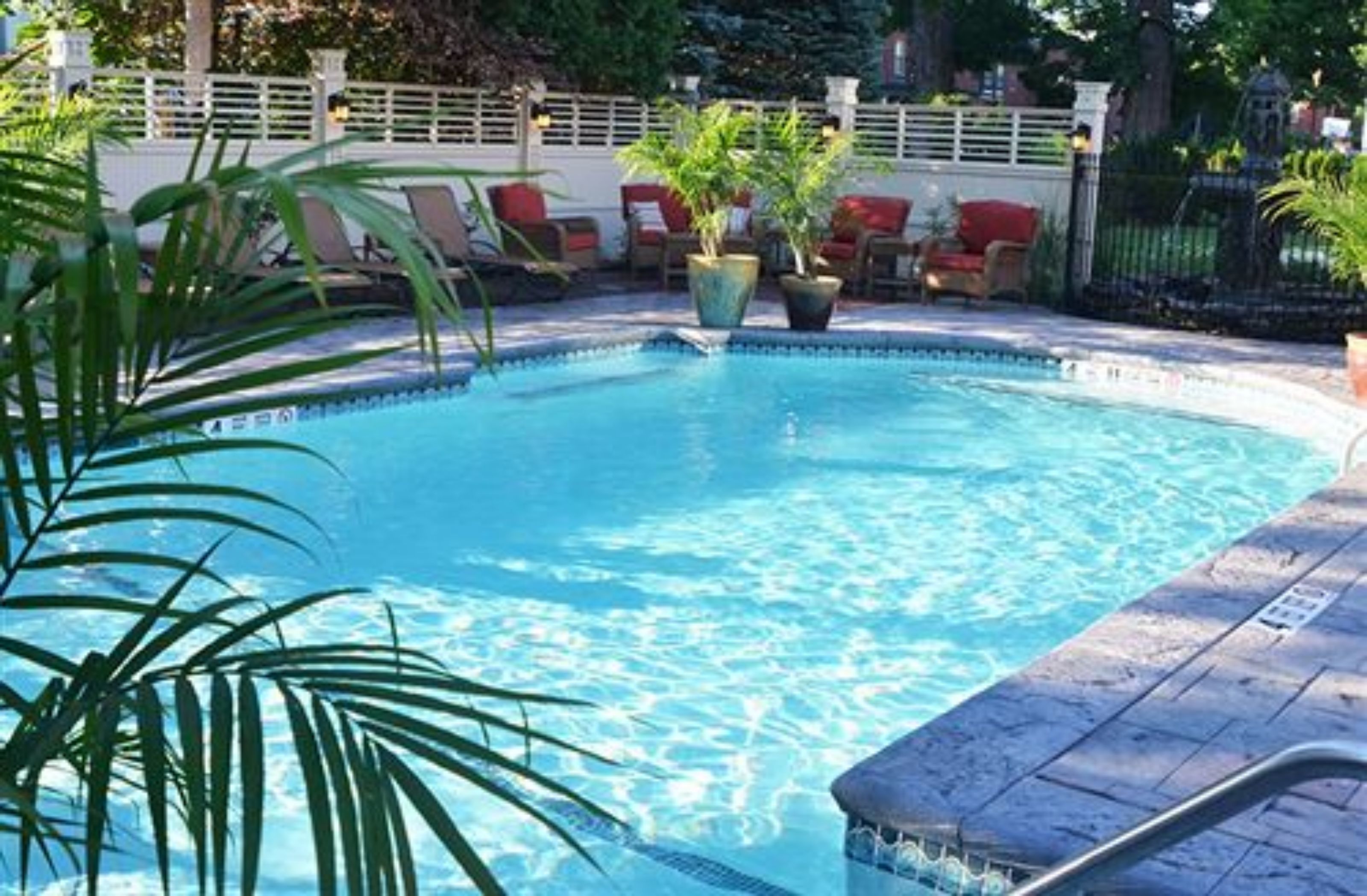 A swimming pool with lounge chairs and potted plants.