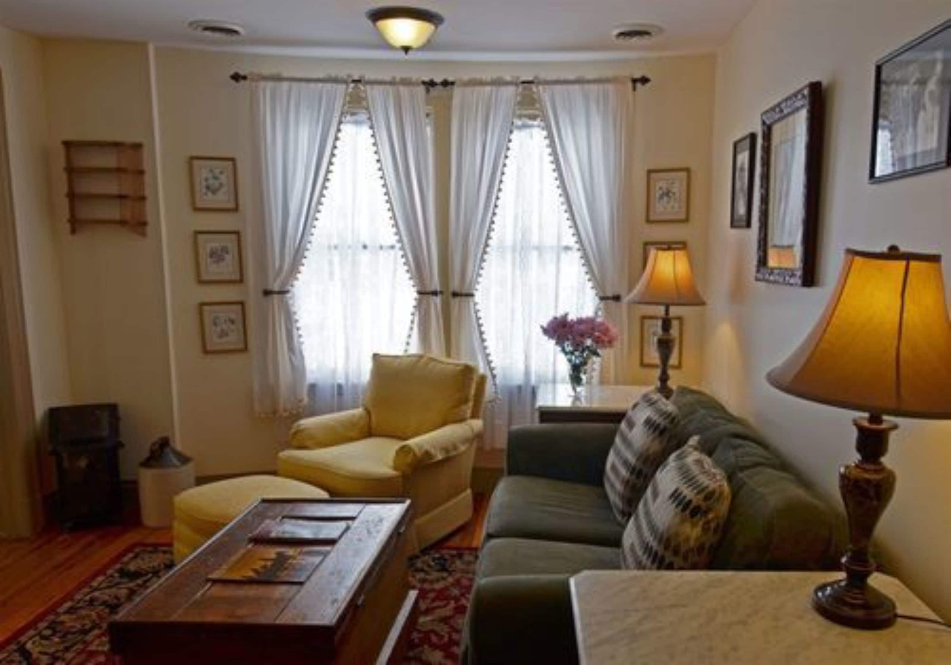 Una sala de estar con sofá, sillón, mesa de centro y lámpara.