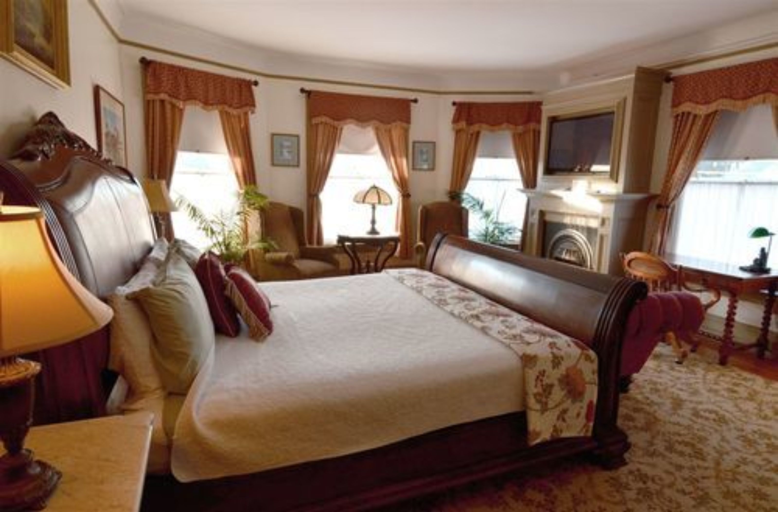 A spacious hotel room with a large bed, a sitting area with a chair and a table, a fireplace, and a television.
