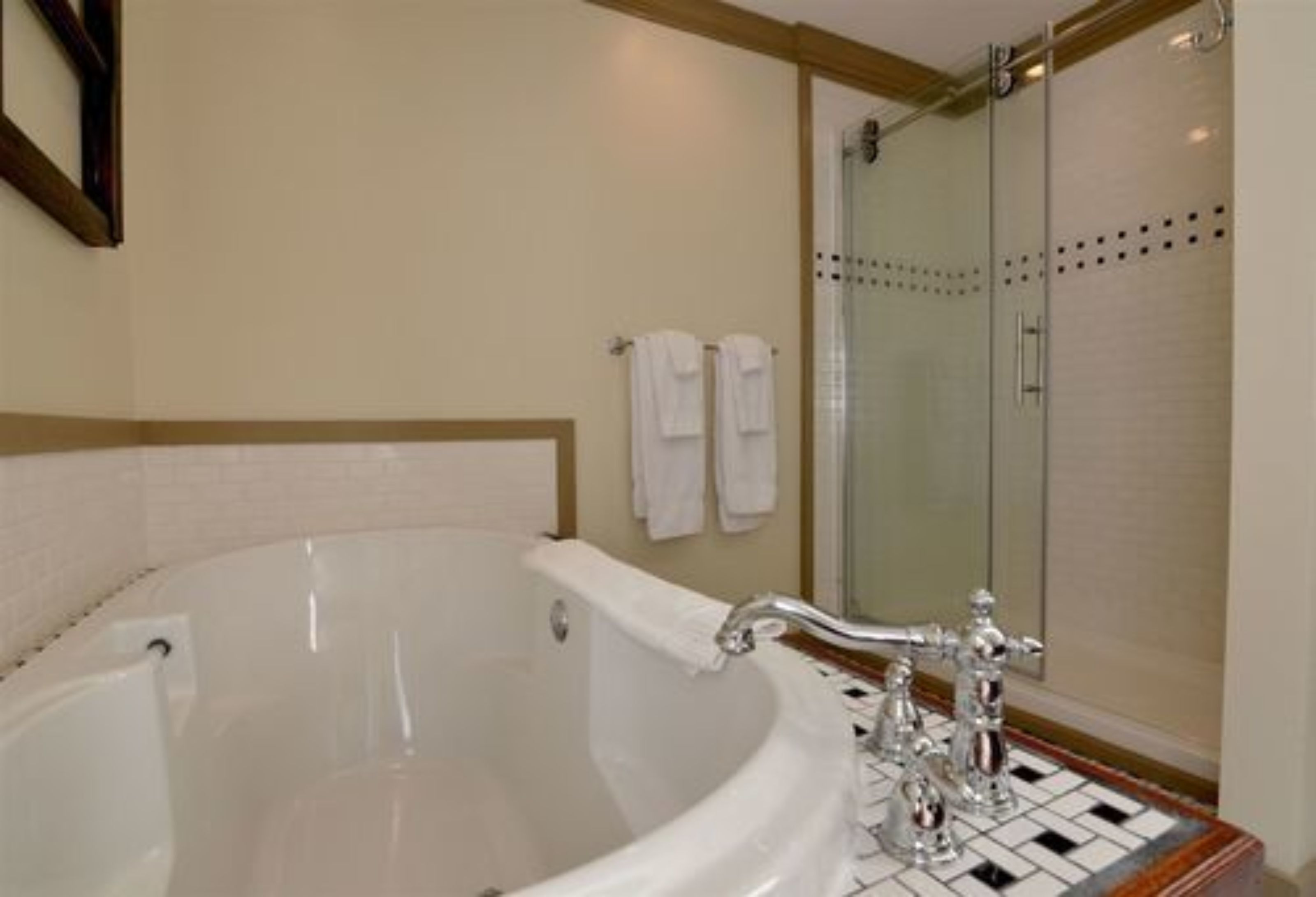 A bathroom with a large white bathtub, a glass shower enclosure, and a tiled floor.
