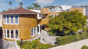 A modern house with a curved wooden facade, a stone pathway, and lush greenery. - Cardiff by the Sea Lodge (Cardiff-by-the-Sea)