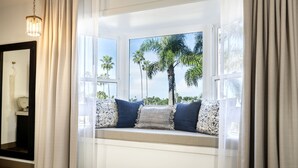 A room with a window seat, white curtains, and a chandelier. - Cardiff by the Sea Lodge (Cardiff-by-the-Sea)
