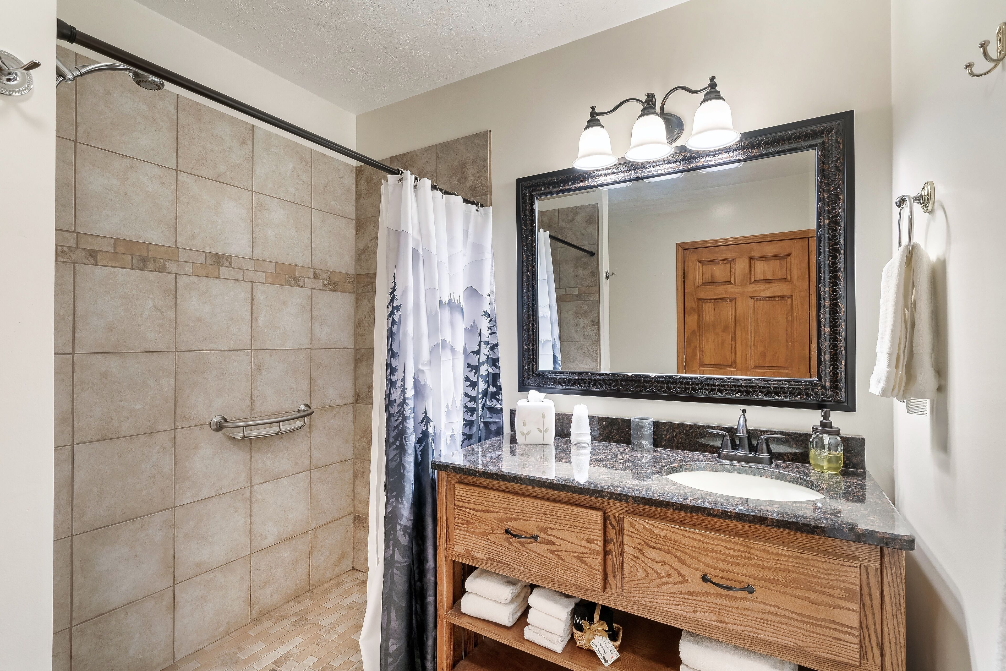 A bathroom with a shower, a sink with a mirror, and a towel rack.