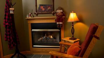 A cozy room with a fireplace, a chair, a lamp, and a red plaid jacket hanging on a rack.