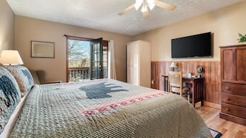 Ein Schlafzimmer mit Bett, Deckenventilator, Fernseher, Schreibtisch und Kleiderschrank.