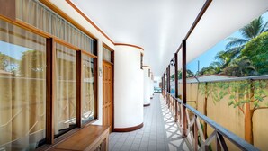 A corridor with large windows, a wooden bench, and a mural of trees. - Hotel Trident Poseidon (Jacó)