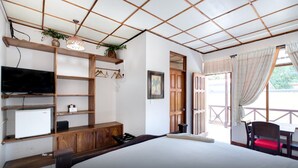 A bedroom with a bed, a TV, a desk, and a window with curtains. - Hotel Trident Poseidon (Jacó)