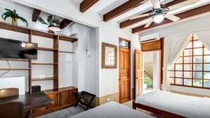 A bedroom with a bed, a desk, a TV, and a ceiling fan. - Hotel Trident Poseidon (Jacó)