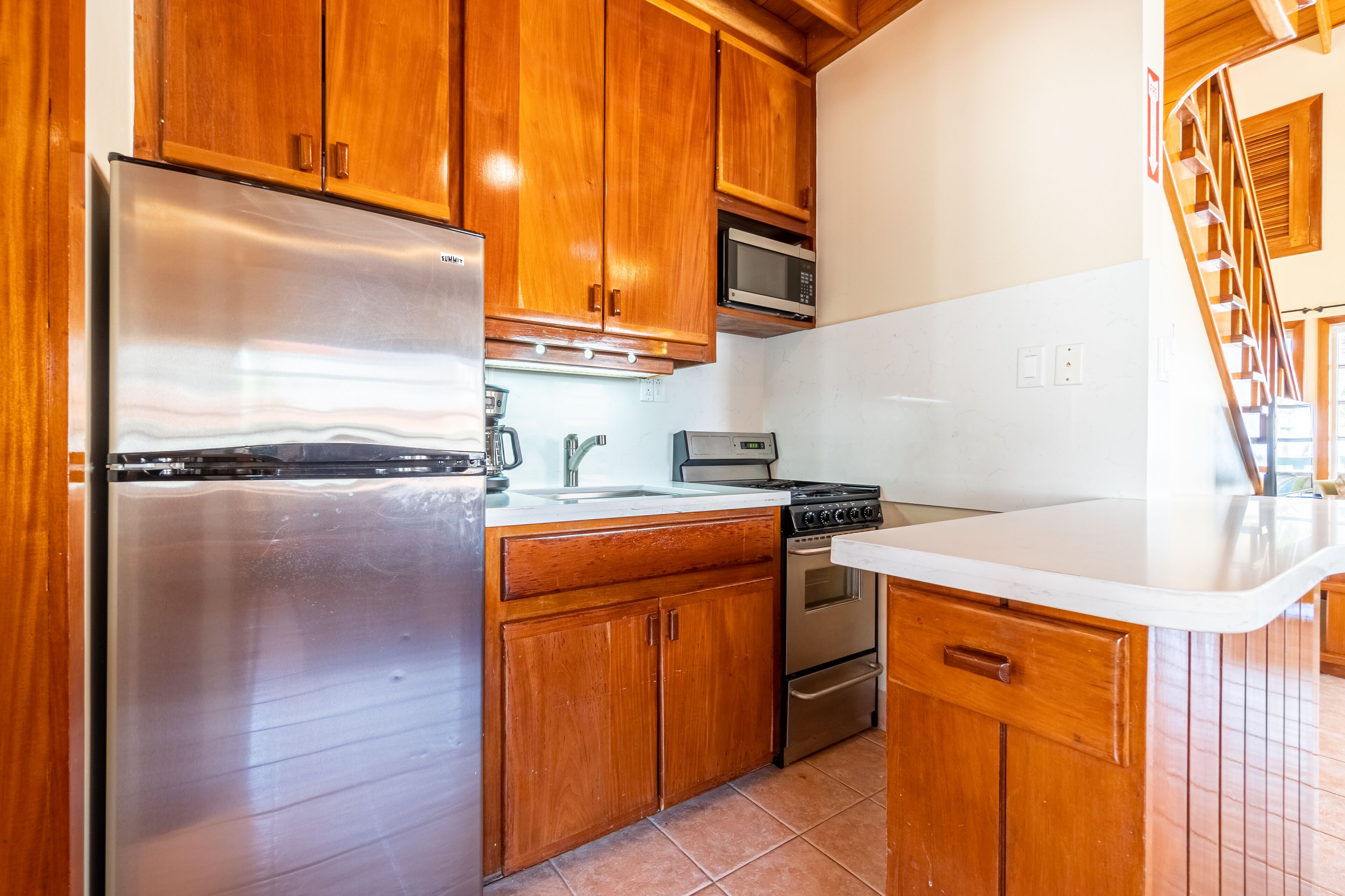 A kitchen with wooden cabinets, stainless steel appliances, and a white countertop.