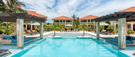 Una piscina al aire libre, sombrillas, sillones reclinables de piscina