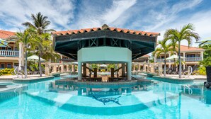 A swimming pool with a gazebo in the center, surrounded by palm trees and a building with a red-tiled roof. - Belizean Shores Resort (San Pedro)