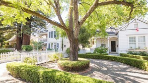 A well-maintained garden with a large tree, neatly trimmed hedges, and a white picket fence. - Inn St Helena (St. Helena)