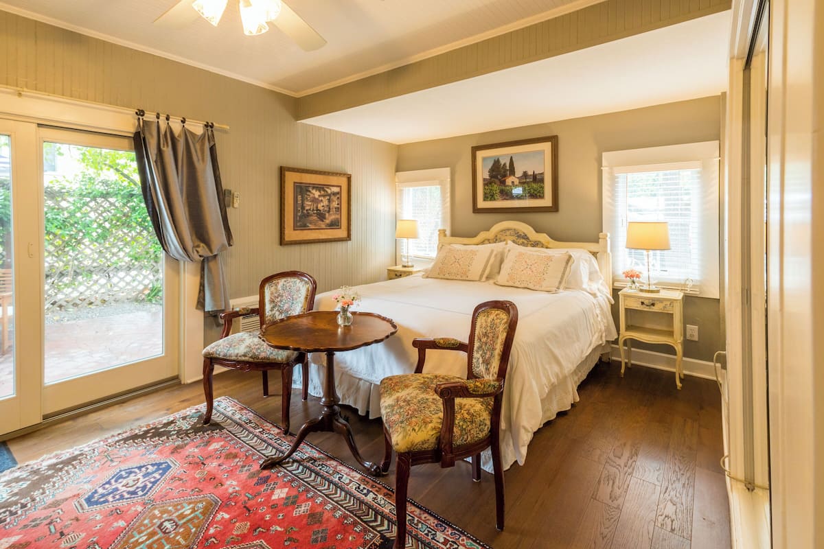 A bedroom with a large bed, two chairs, a small table, and a rug.