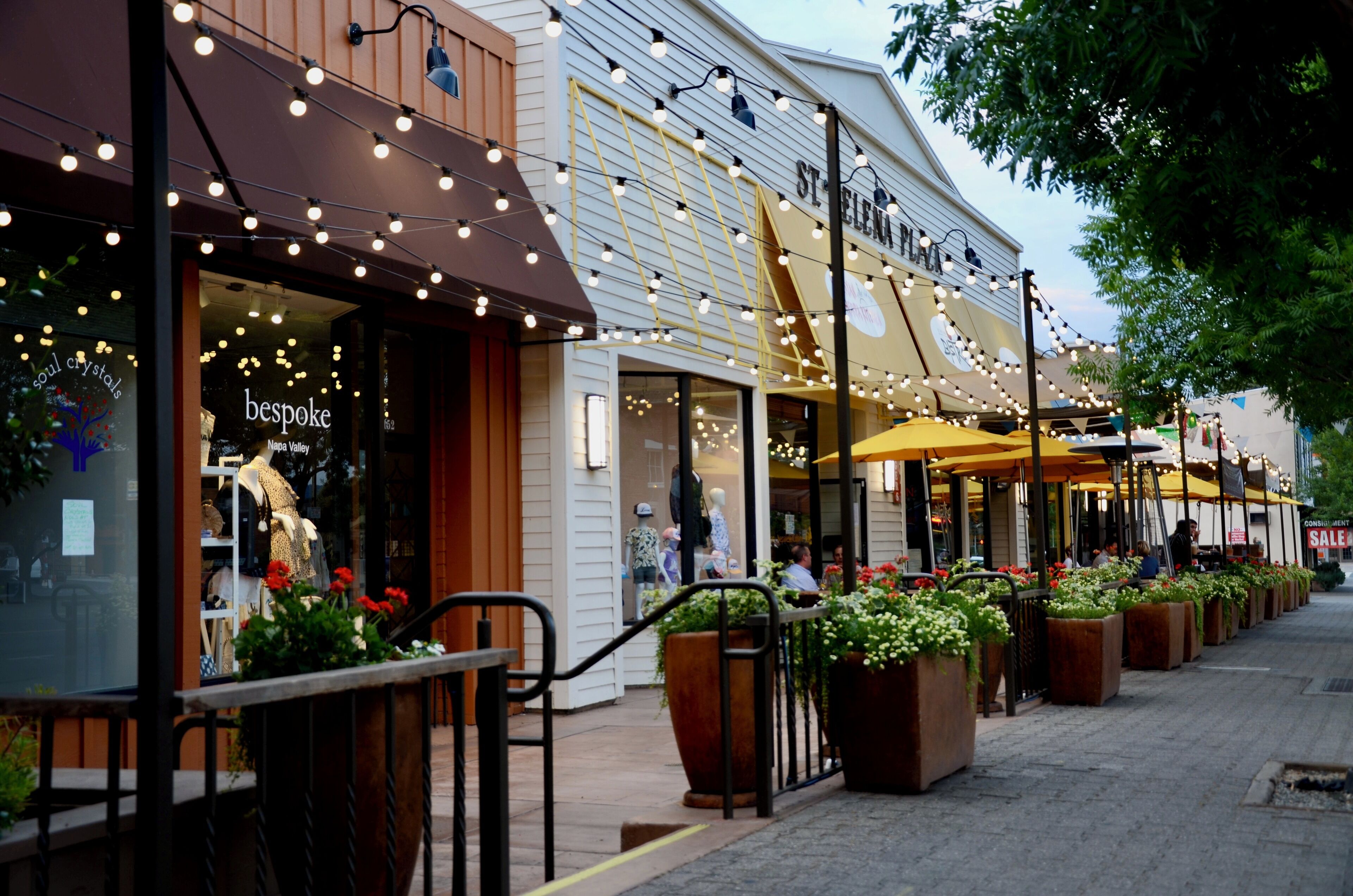 Une rue commerçante où l’on trouve des boutiques, dont une nommée « bespoke », et un restaurant avec une terrasse.