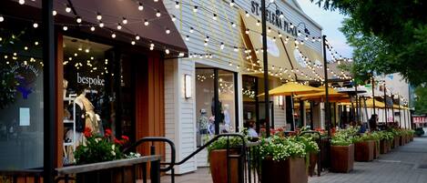 Une rue commerçante où l’on trouve des boutiques, dont une nommée « bespoke », et un restaurant avec une terrasse.