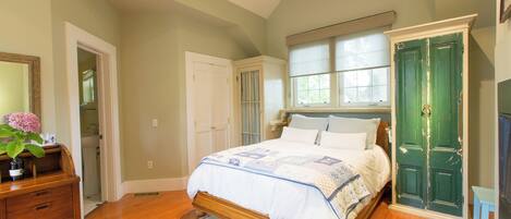 A bedroom with a bed, dresser, and a green door.