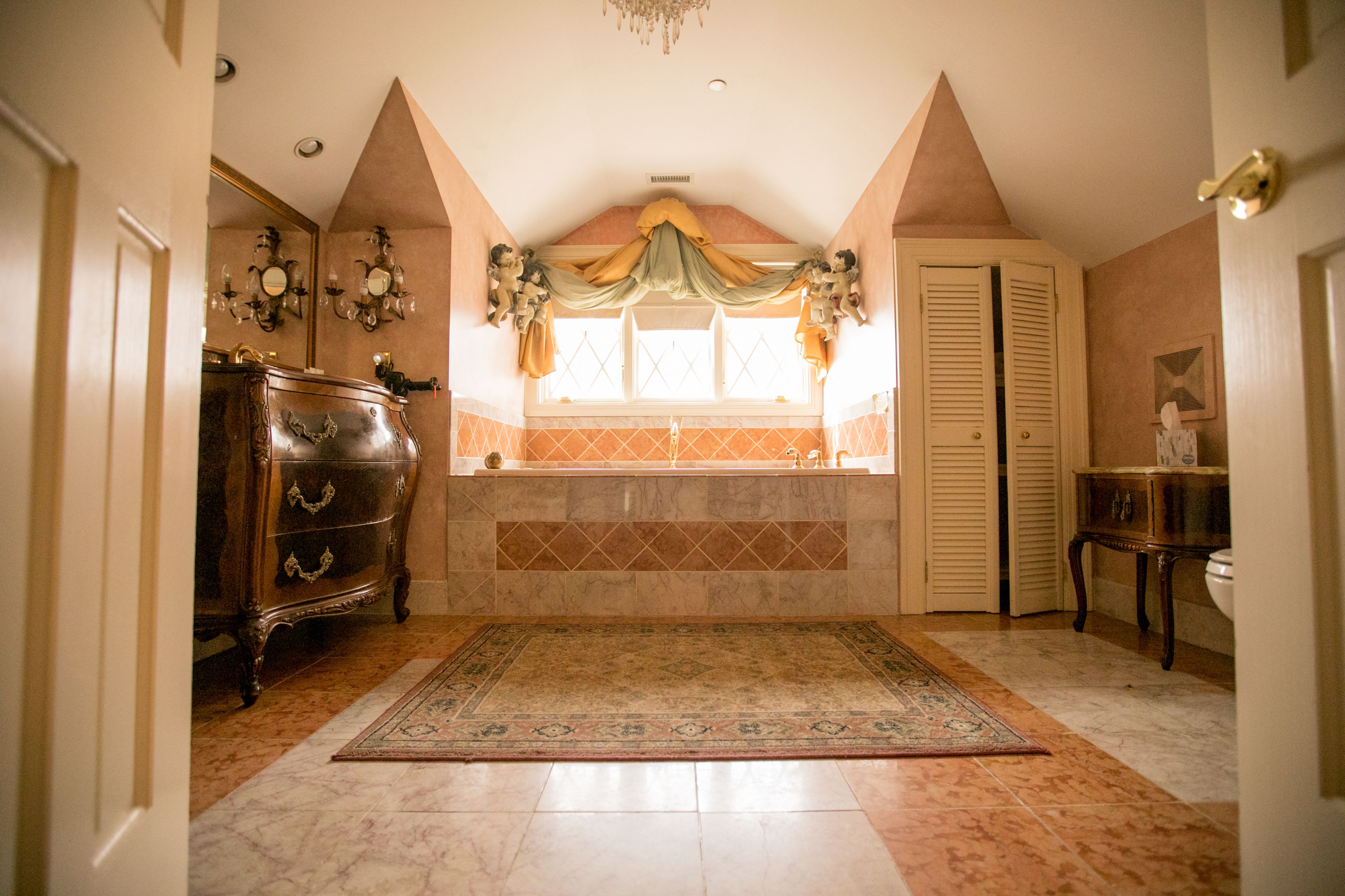A bathroom with a bathtub, a vanity, and a chandelier.