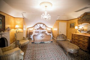 Classic bedroom with a large bed, bench, and chandelier.