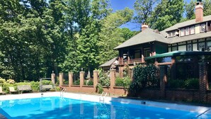 A swimming pool with a brick wall and a wooden deck.