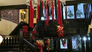 A grand staircase with a chandelier, red ribbons, and a view of the outside.