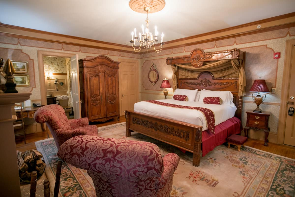 A traditional bedroom with a four-poster bed, a chandelier, and classic furnishings.
